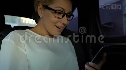成功的女士在开车时通过手机阅读好消息，快乐视频
