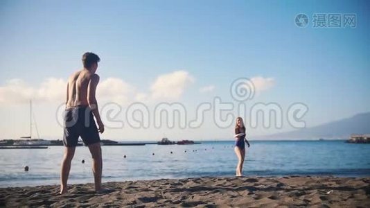 一个年轻人和他的女朋友在海滩上玩飞盘视频