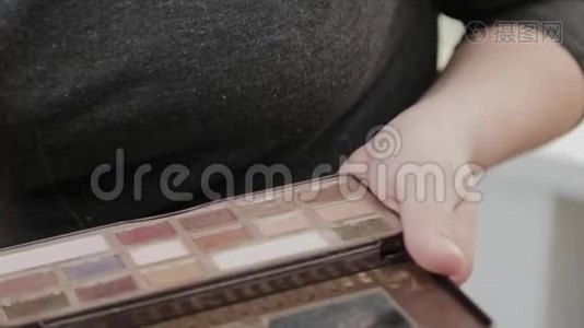 专业的化妆师女人用她手中的调色板化妆。视频