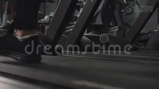 在健身房跑步机上以轻快的步伐接近男人的双脚，追踪左边。视频