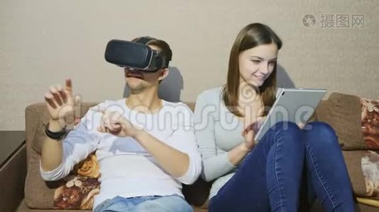 男人用虚拟现实设备，而女人用数字平板电脑打字视频