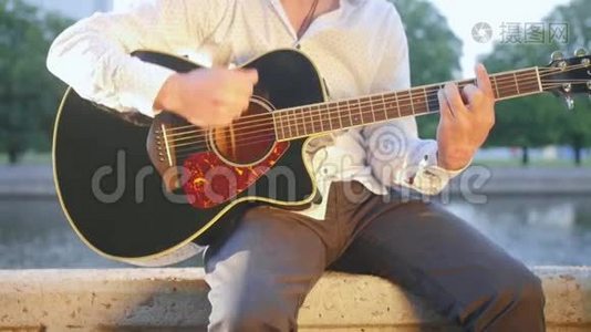 人坐在公园里的石砌木板路上弹吉他.. 近距离射击。视频