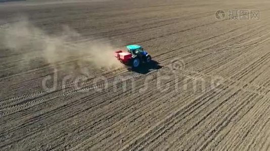 农用拖拉机在大轮子上的空中视野跨越肥沃的农田，传播矿物肥料视频