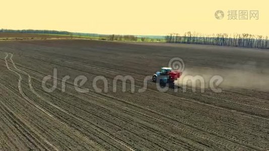 农用拖拉机在大轮子上的空中视野跨越肥沃的农田，传播矿物肥料视频