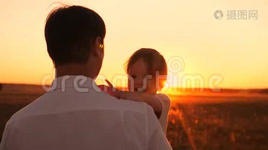 爸爸在日落时抱着小女儿。 波普和太阳的孩子们在公园里散步。视频