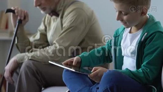 上瘾的男孩玩平板电脑游戏，悲伤的祖父看着他，谴责视频