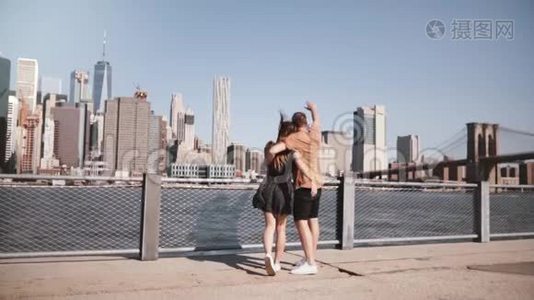 快乐的欧洲游客夫妇站在拥抱，举起双臂欣赏史诗般的曼哈顿景观在纽约，美国慢动作。视频