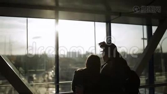 机场游客剪影。 男孩和女孩站在窗户前，兴高采烈地说话。 妇女视频