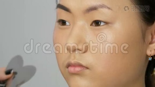 专业造型师化妆师，用特殊的画笔描绘眉毛，眉毛阴影为亚洲女孩模特的脸视频