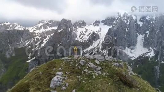 徒步旅行者站在山顶上，看着白雪皑皑的群山视频