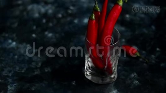 明亮的红色辣椒在透明的玻璃上深蓝色的背景。 颜色趋势视频