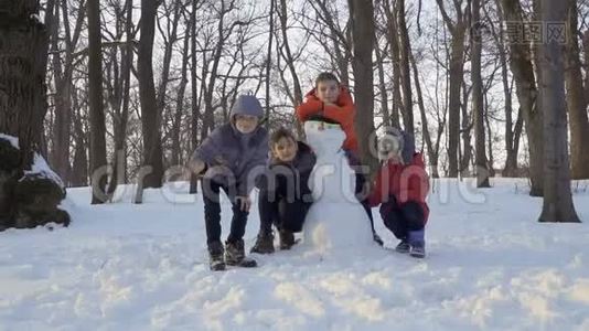 冬天公园里，四个穿着紧身衣的男孩在堆雪人的时候视频