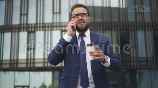 在商业区，成功的商务人士打电话，手里拿着一杯咖啡站在外面。视频