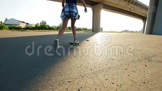 美丽的女孩骑着滑板在桥下的太阳，在腿的框架视频