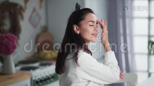 穿着浴袍的年轻女子脸上涂着奶油，做面部按摩视频