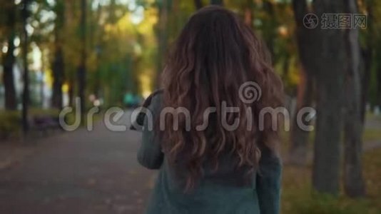 一个留着卷发的漂亮女孩走在秋天的小巷里，微笑着视频