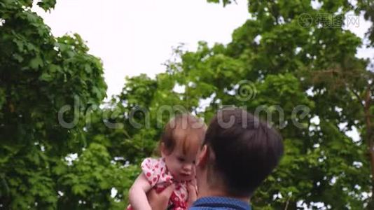 爸爸在公园夏天和孩子玩。 小女孩在爸爸的手里跳着，笑着。 慢动作视频