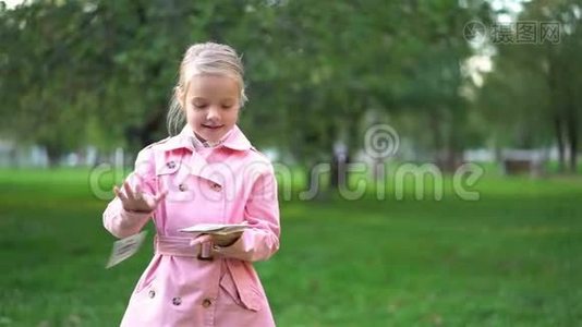穿粉色衣服的小女孩在公园里扔掉钞票视频