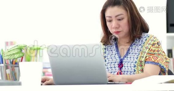 年轻的亚洲女商人在家里用笔记本电脑工作。 亚洲女人下班后伸展自己。视频