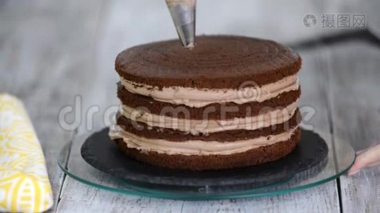 奶油被挤在巧克力蛋糕上。 把奶油挤在蛋糕上视频