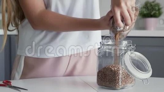 将荞麦倒入一个玻璃罐中存放。视频