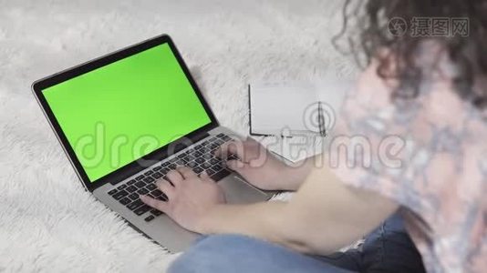 这位年轻女子使用笔记本电脑和键盘打字，工作场所在家里。 带绿色屏幕的笔记本电脑视频
