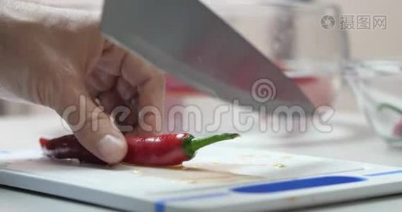 一个厨师的特写手切一个新鲜的热红辣椒辣椒与刀在一个切割板。 素食健康营养食品视频
