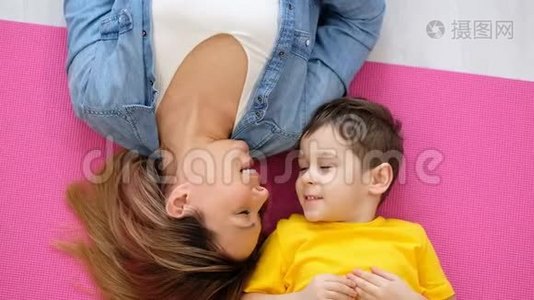 妈妈和儿子躺在家里的地板上。 一个快乐的妈妈和她儿子的视频肖像。视频