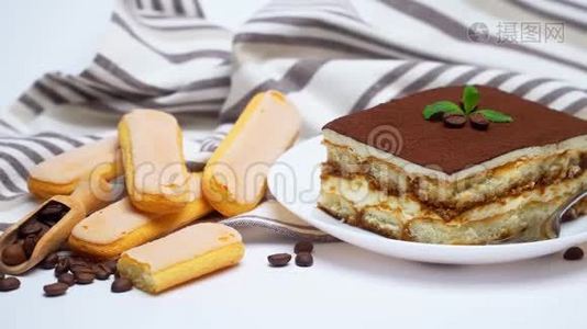泰拉米苏甜点部分在陶瓷盘子，萨维亚迪饼干和咖啡豆隔离在白色视频