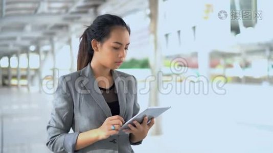 年轻工作妇女站在室外使用平板电脑视频