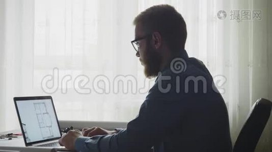 在笔记本电脑上靠窗户设计蓝图的建筑师视频