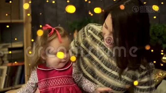 年轻的，迷人的，微笑的女人妈妈带着一个快乐的，甜美的孩子在黄色后面的美丽的新年工作室里视频