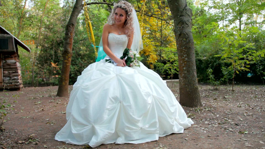 新娘坐在公园的秋千上视频