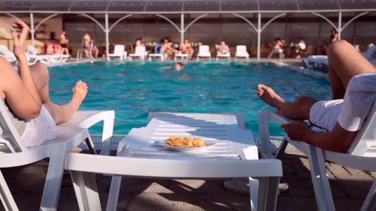 成年夫妇享受放松度假游泳池边吃薯片视频