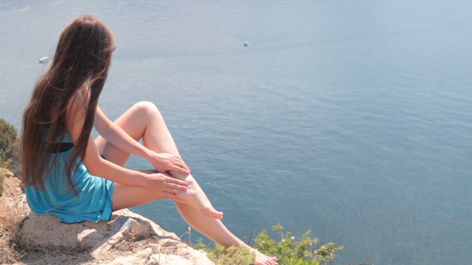 赤脚的年轻女人躺在海边的山顶上视频
