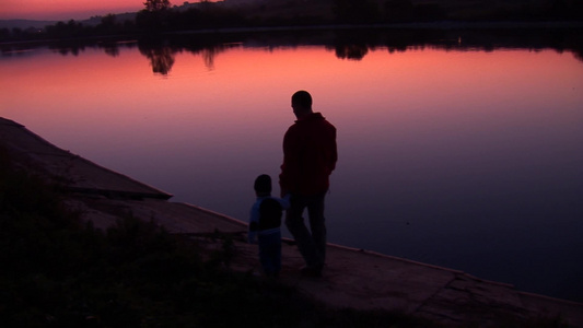 傍晚爸爸牵着孩子在湖边行走的背影视频