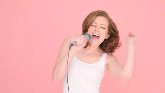 女人在粉色的背景下唱歌视频