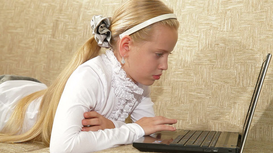 金发小女孩在家用笔记本电脑视频