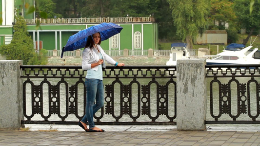 美丽的女孩在水边摆着雨伞视频