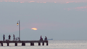 日落时人们在码头上谈话钓鱼或骑自行车29秒视频