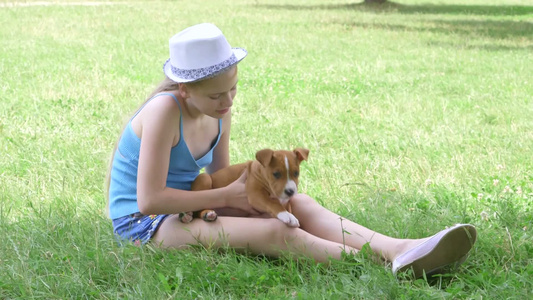 小女孩坐在草坪上和小狗玩耍视频
