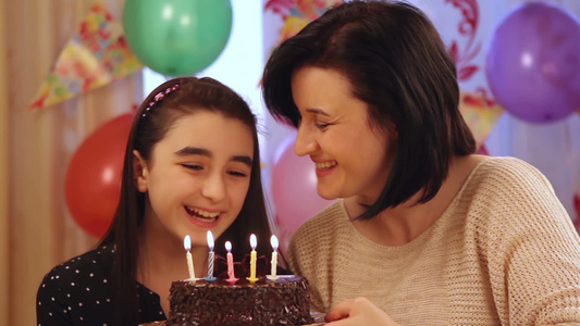 快乐的母亲和女儿吹生日蛋糕的蜡烛视频