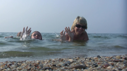 女儿和妈妈快乐地躺在海水里视频