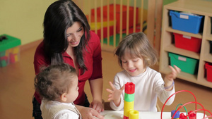 女教师在幼儿园陪幼儿和女孩玩积木玩具12秒视频