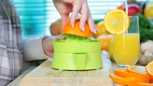 女性手在榨汁机上挤压橙汁15秒视频