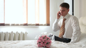 男人坐在放着鲜花的床上打电话10秒视频