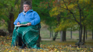 老妇人坐在公园椅子上看书15秒视频