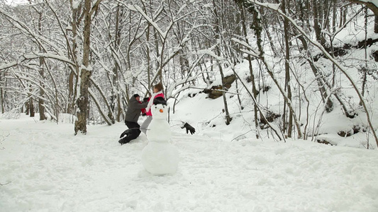 冬天雪地里堆雪人的青年夫妇[青年一代]视频