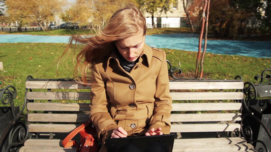 女孩用她的笔记本电脑在长椅上工作视频