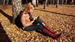 秋天坐在树林里使用平板电脑的女孩10秒视频